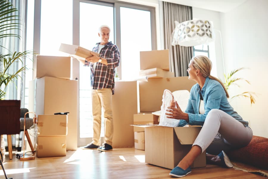 Elderly couple smiling as they unpack boxes