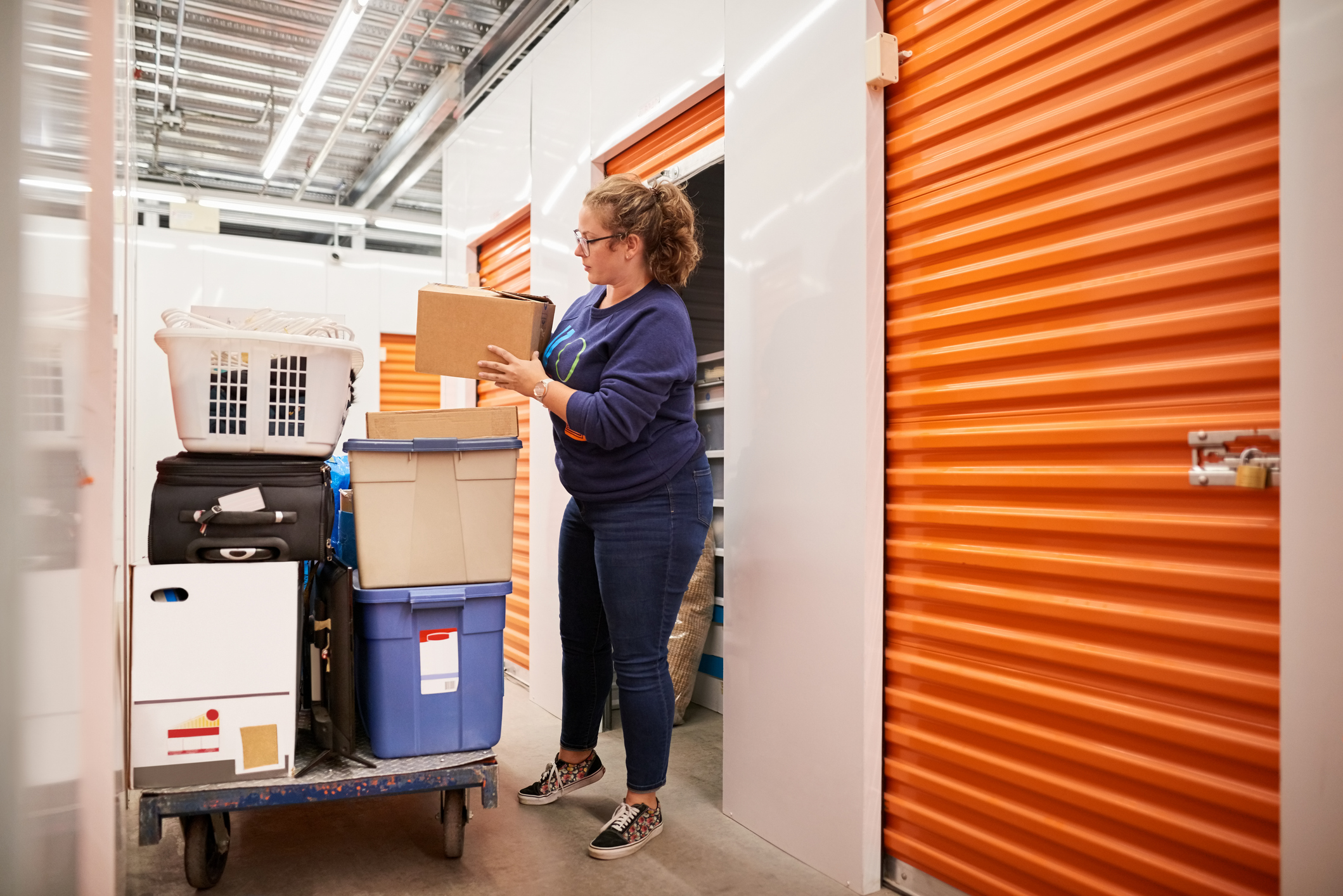 Person picking up box from trolley and moving it into storage unit